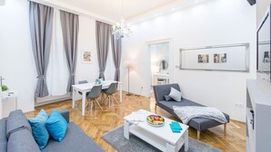 A modern living room with a grey sofa, a dining table, and a grey armchair. - Dominik Apartment (Budapest)
