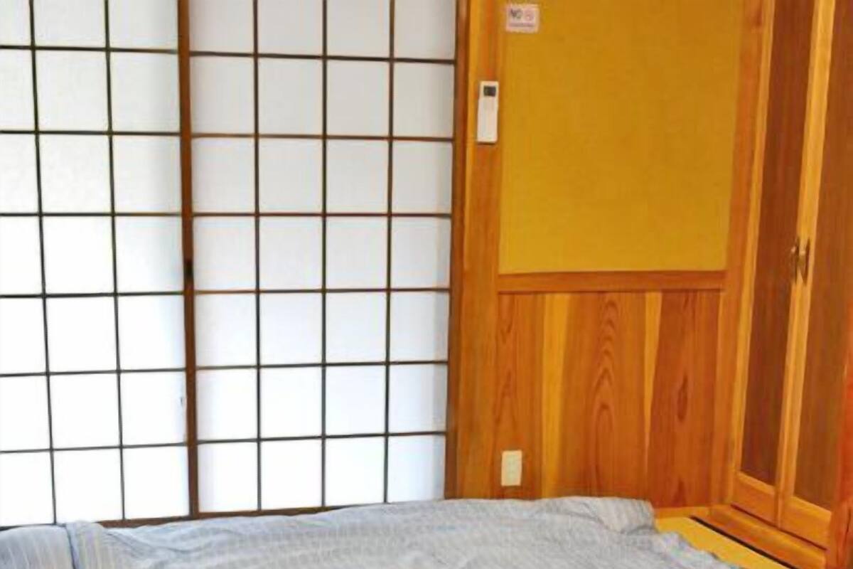 A room with a large bed, a wooden wardrobe, and a shoji screen.