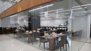 A modern dining area with glass partitions, multiple tables, and chairs. - Pacific Hotel (Yangon)