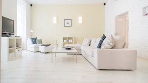 A modern living room with a white sofa, a coffee table, and a television on a stand.