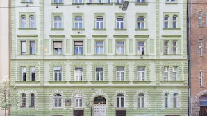 A multi-story building with a symmetrical facade, featuring evenly spaced windows and a central entrance with a double door.