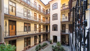 A courtyard with multiple balconies, potted plants, and a central staircase.