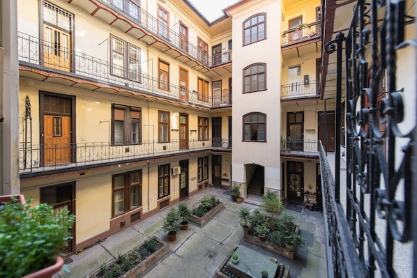 A courtyard with multiple balconies, potted plants, and a central staircase.