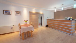 Un área de recepción con un mostrador de madera, una mesa de comedor con sillas y cuadros en la pared.