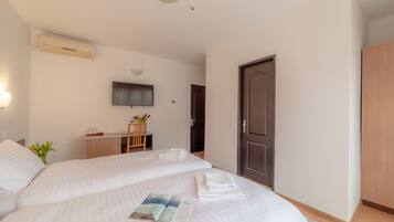 A hotel room with two beds, a desk, a TV, and a wardrobe.