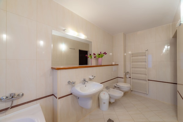 A modern bathroom with a sink, bidet, toilet, and a towel rack.