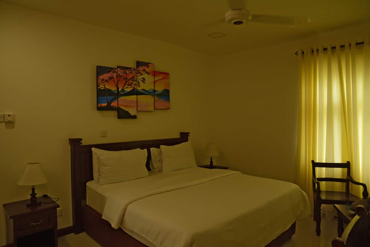 A hotel room with a bed, a nightstand, a chair, and a painting on the wall.