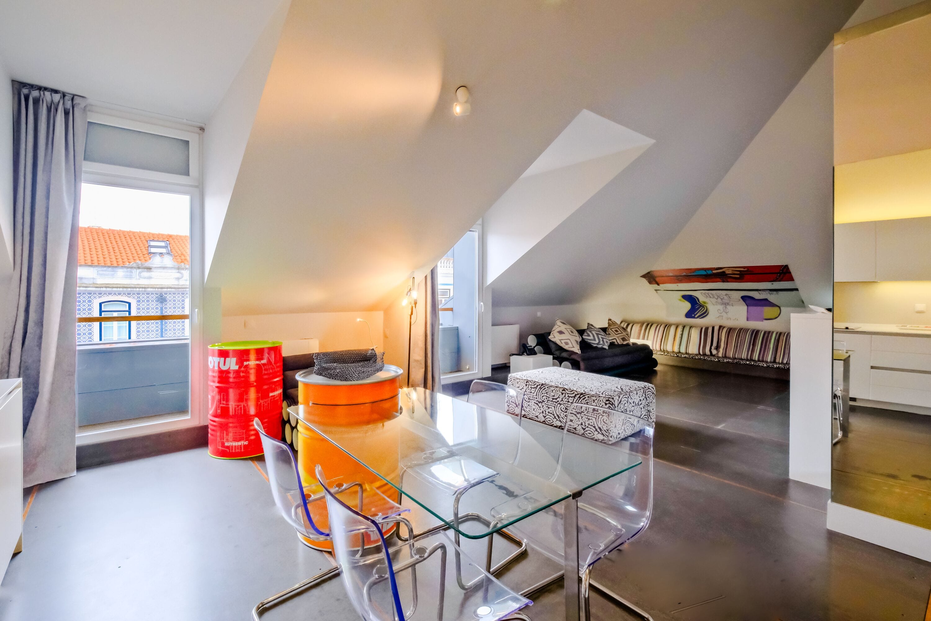 A modern apartment with a glass dining table, a sofa, and a kitchen area.