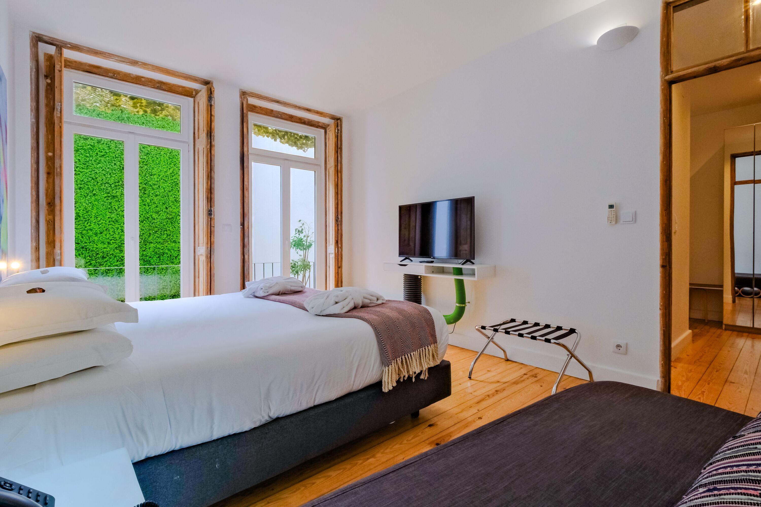 A modern bedroom with a large bed, a TV, and a small table.