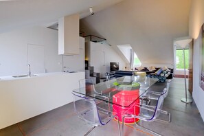 A modern kitchen with a glass dining table, white cabinetry, and a visible kitchen island. - Chiado Arty flats (Lisbon)