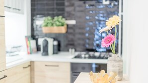 Eine moderne Küche mit weißer Arbeitsplatte, einer Blumenvase und einer hängenden Pflanze.