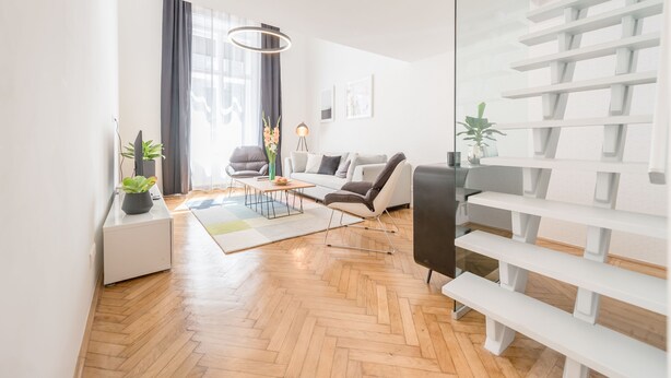 Ein modernes Wohnzimmer mit einer Couch, einem Couchtisch und einer Glastrennwand mit Regalen.