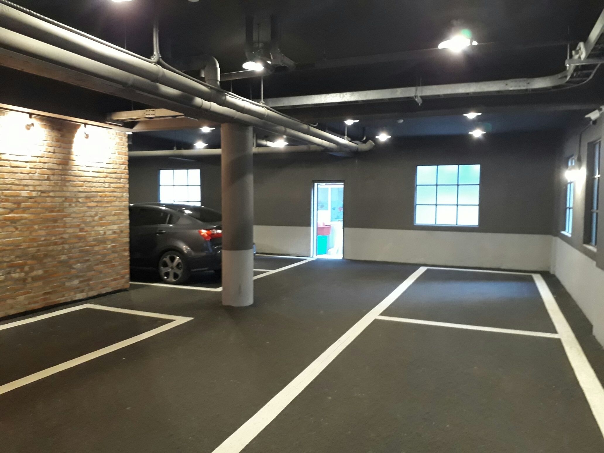 Un garaje para coches con un vehículo estacionado en una de las plazas.