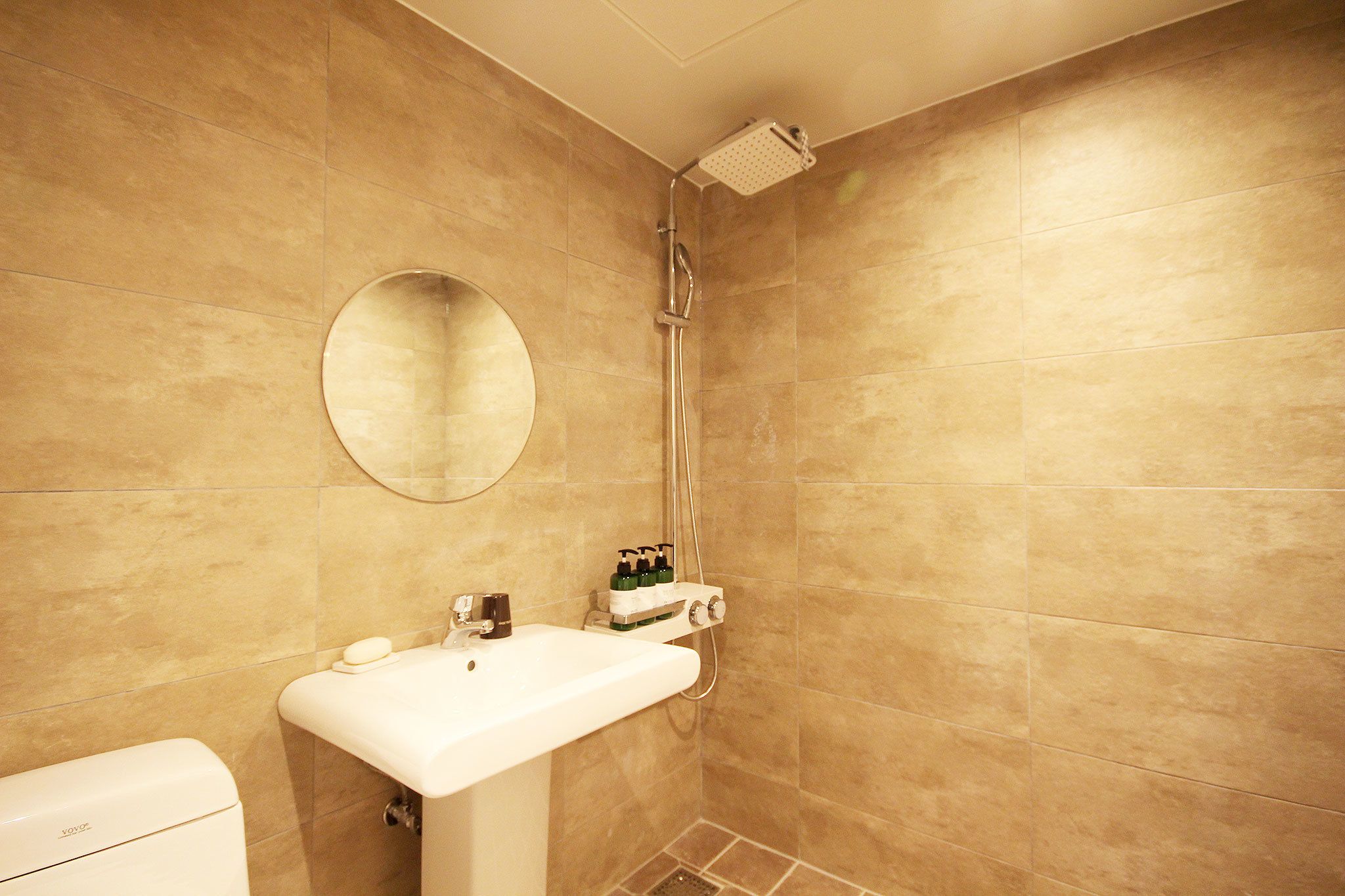 A bathroom with a sink, mirror, and shower.