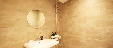 A bathroom with a sink, mirror, and shower.