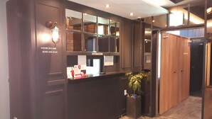 A reception desk with a dark wood finish, a glass partition, and a sign labeled "Information." - 2day Hotel (Geoje)