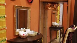 A room with an orange wall, a mirror, a table with a basket, and a chair. - Nonnaisuan resort (Bangkok)