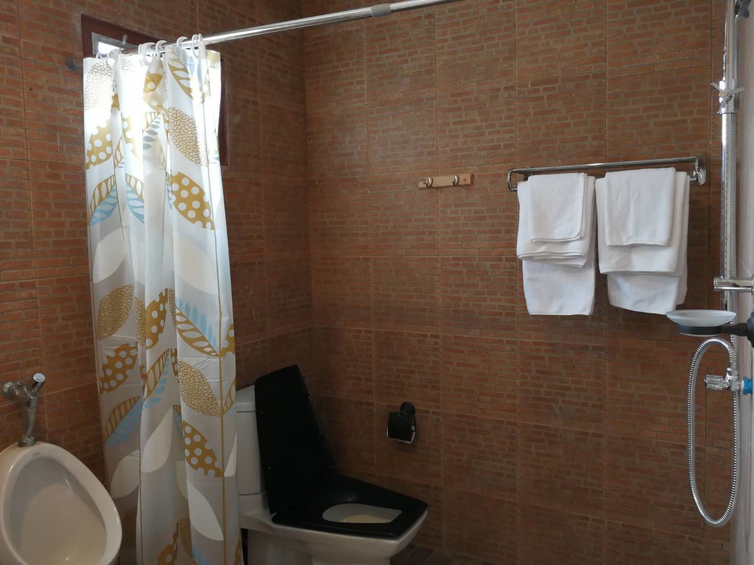 A bathroom with a shower, a toilet, and a urinal.
