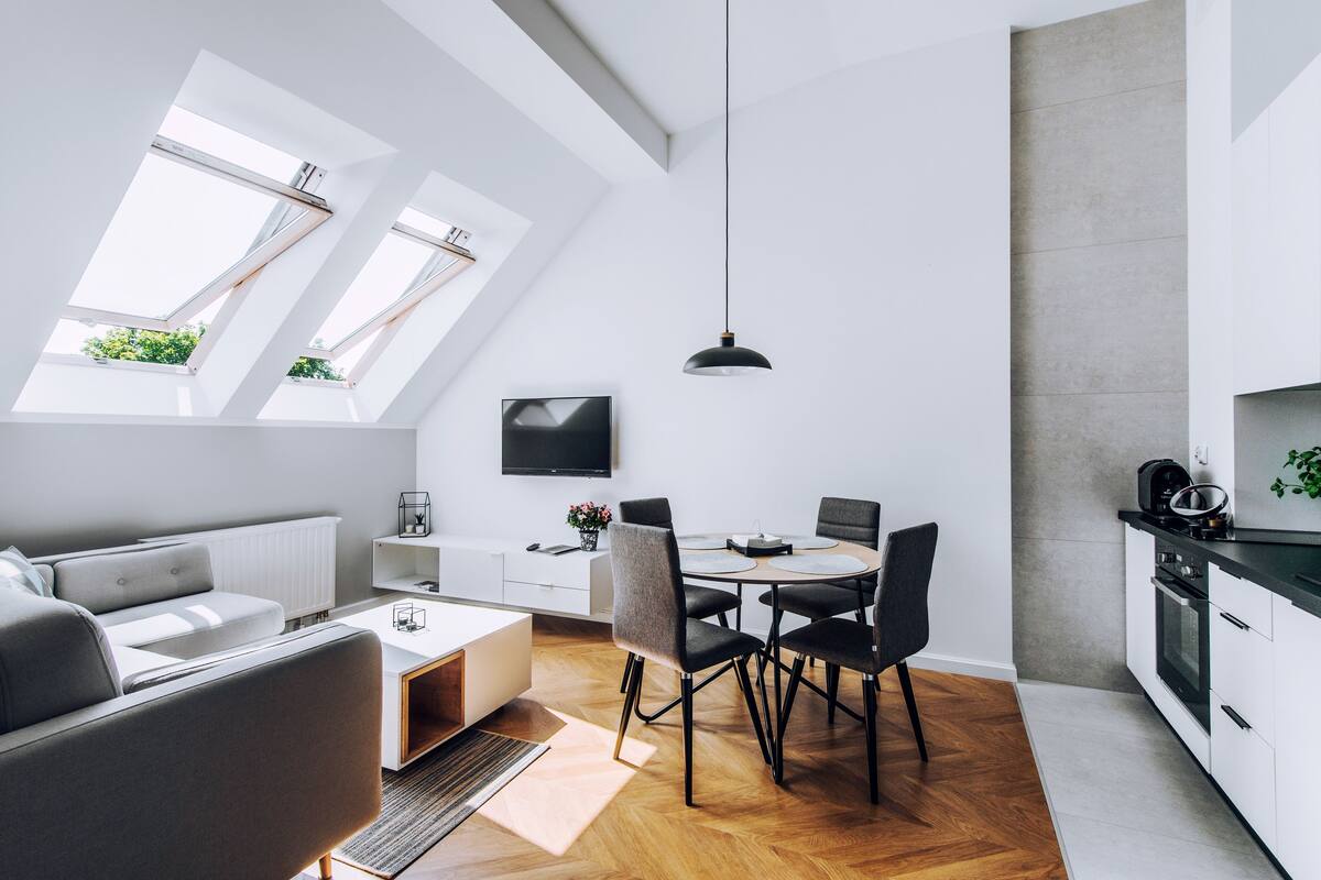 Ein zeitgemäßer Wohnraum mit Essbereich, Küche und großem Fenster mit Oberlichtern.