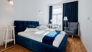 Une chambre à coucher moderne avec un grand lit, une table de chevet, une chaise et une fenêtre avec des rideaux.