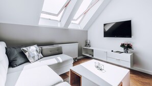 Un salon moderne avec un canapé, une table basse et un téléviseur à écran plat fixé au mur.