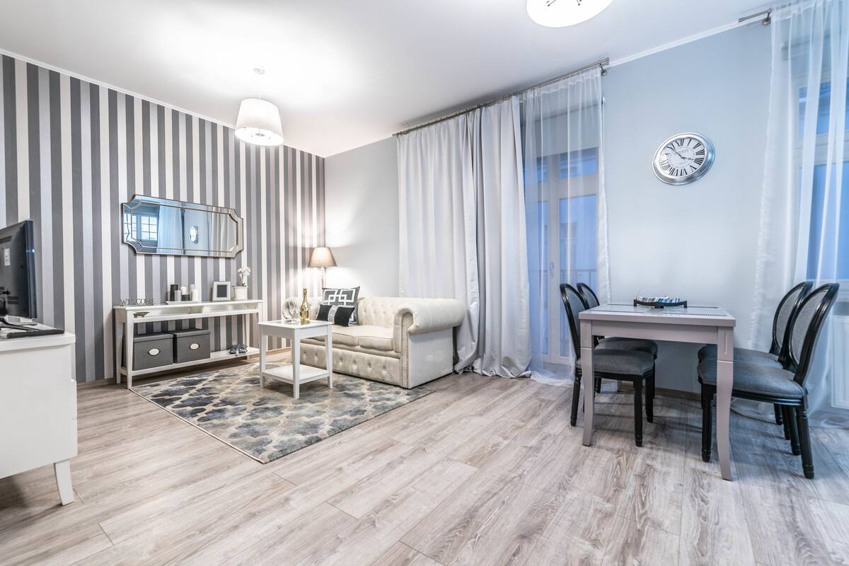Ein modernes Wohnzimmer mit Sofa, Couchtisch, Fernseher und Essbereich.