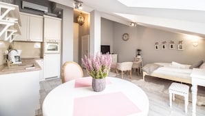 Une pièce moderne et bien éclairée, comprenant un coin repas, une kitchenette et un espace salon confortable avec un lit.