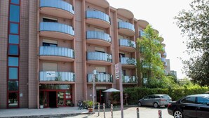 Un hôtel à plusieurs étages, doté de balcons, d’une entrée au niveau du sol et d’un espace de stationnement.