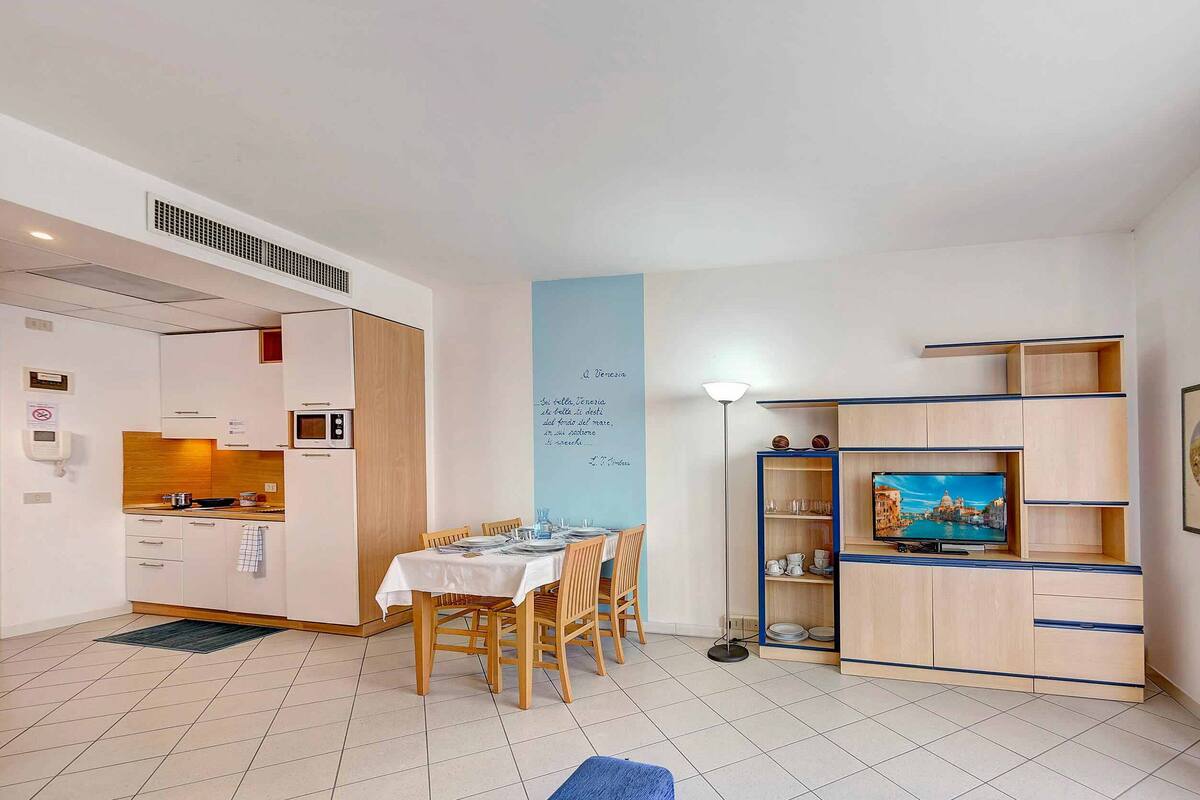 A compact living space with a kitchenette, dining area, and entertainment unit.