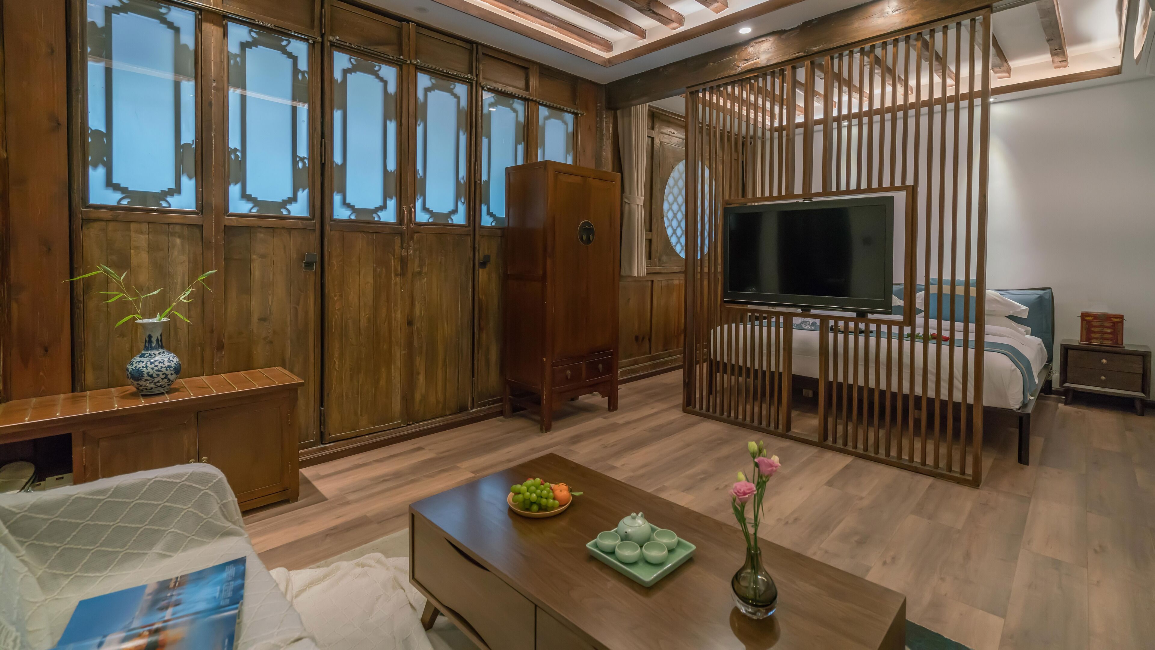 Ein traditionell eingerichtetes Zimmer mit Holzmöbeln, einem Fernseher und einem Bett.