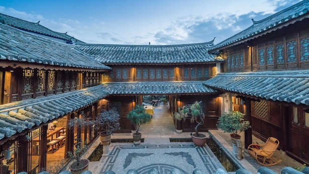 A traditional courtyard with wooden buildings, potted plants, and a tiled floor. - Lize Graceland Artistic Suite Inn (Lijiang)