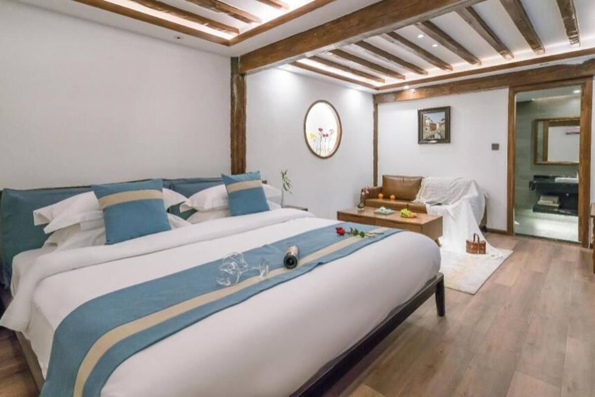 A bedroom with a large bed, a bedside table, a chair, and a mirror.