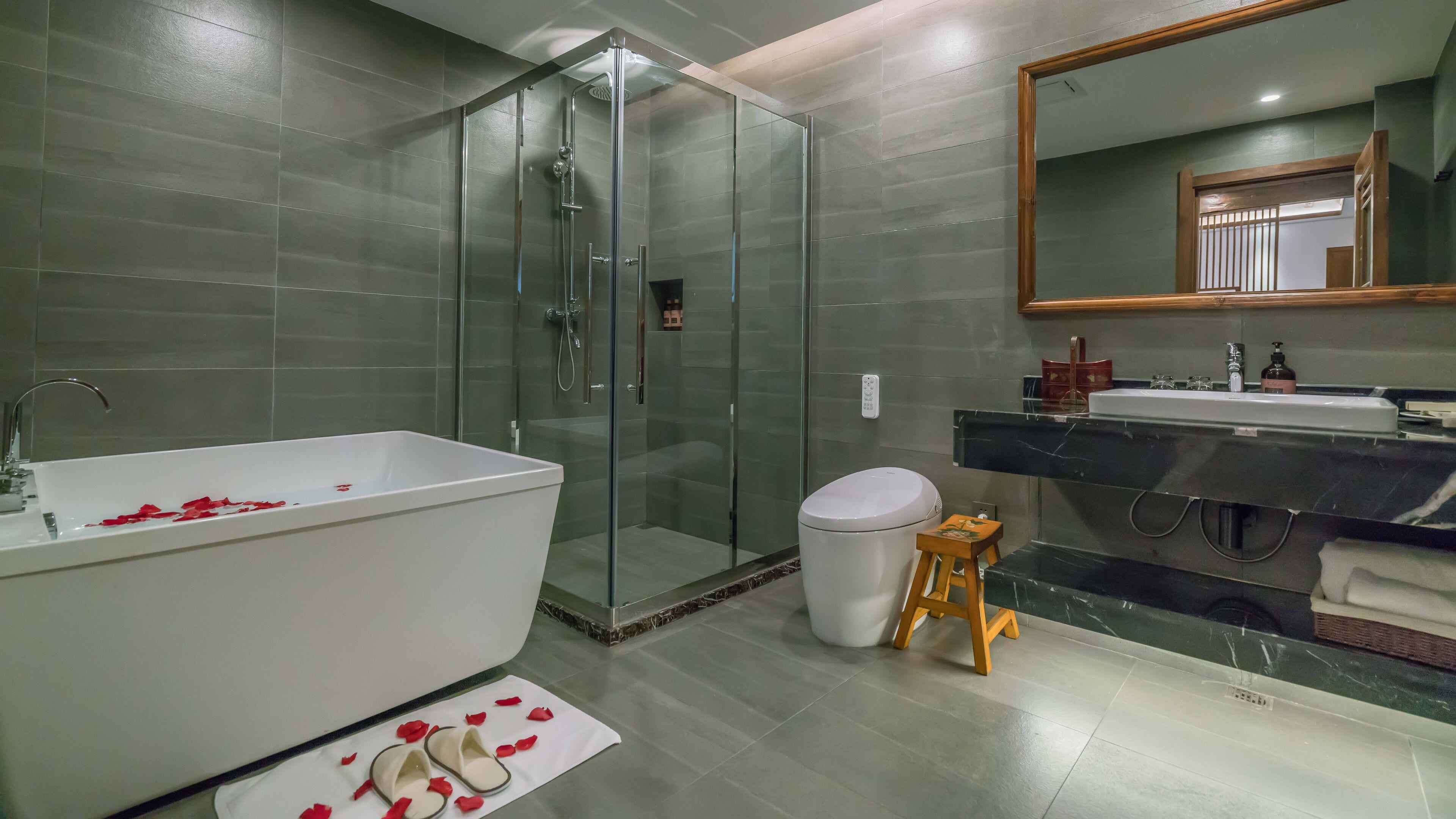 Ein modernes Badezimmer mit einer gläsernen Duschkabine, einer weißen Badewanne und einem Waschtisch mit Spiegel.