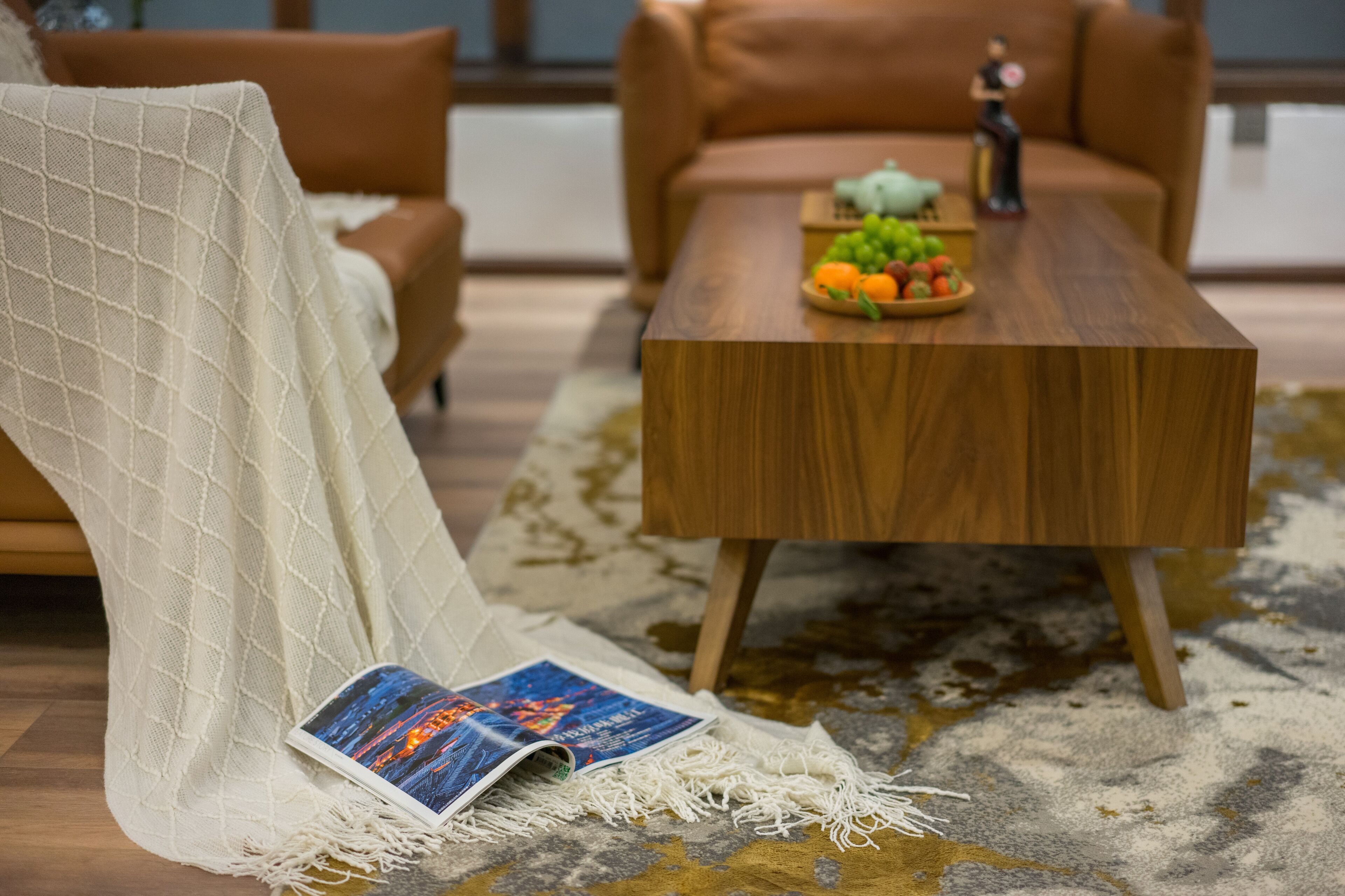 A cozy living room with a wooden coffee table, a patterned rug, and a white knitted chair.