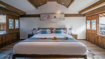 A bedroom with a large bed, wooden beams, a painting, and a nightstand with a lamp.