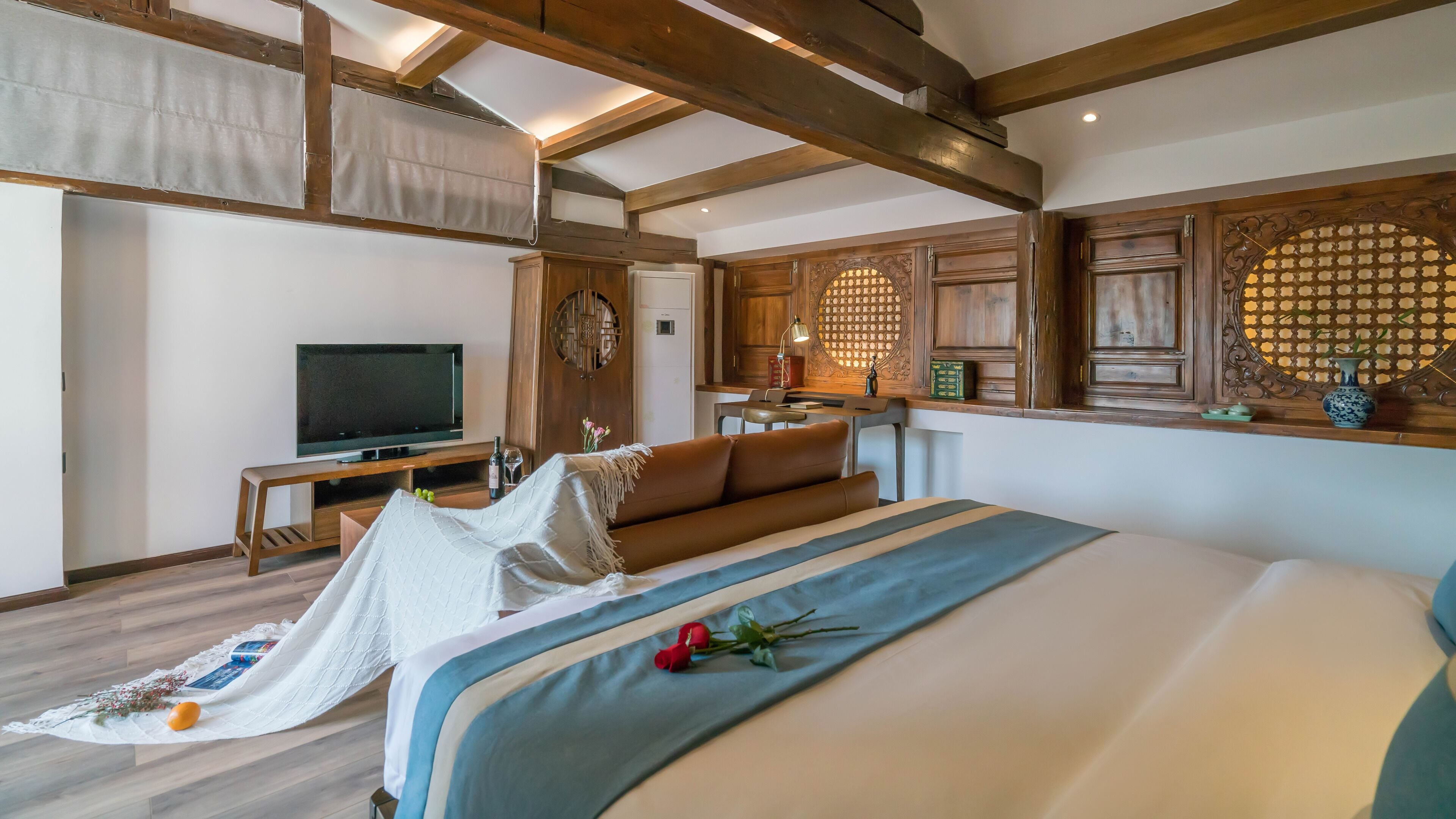 A bedroom with a large bed, a television, and a dining area with wooden cabinets.