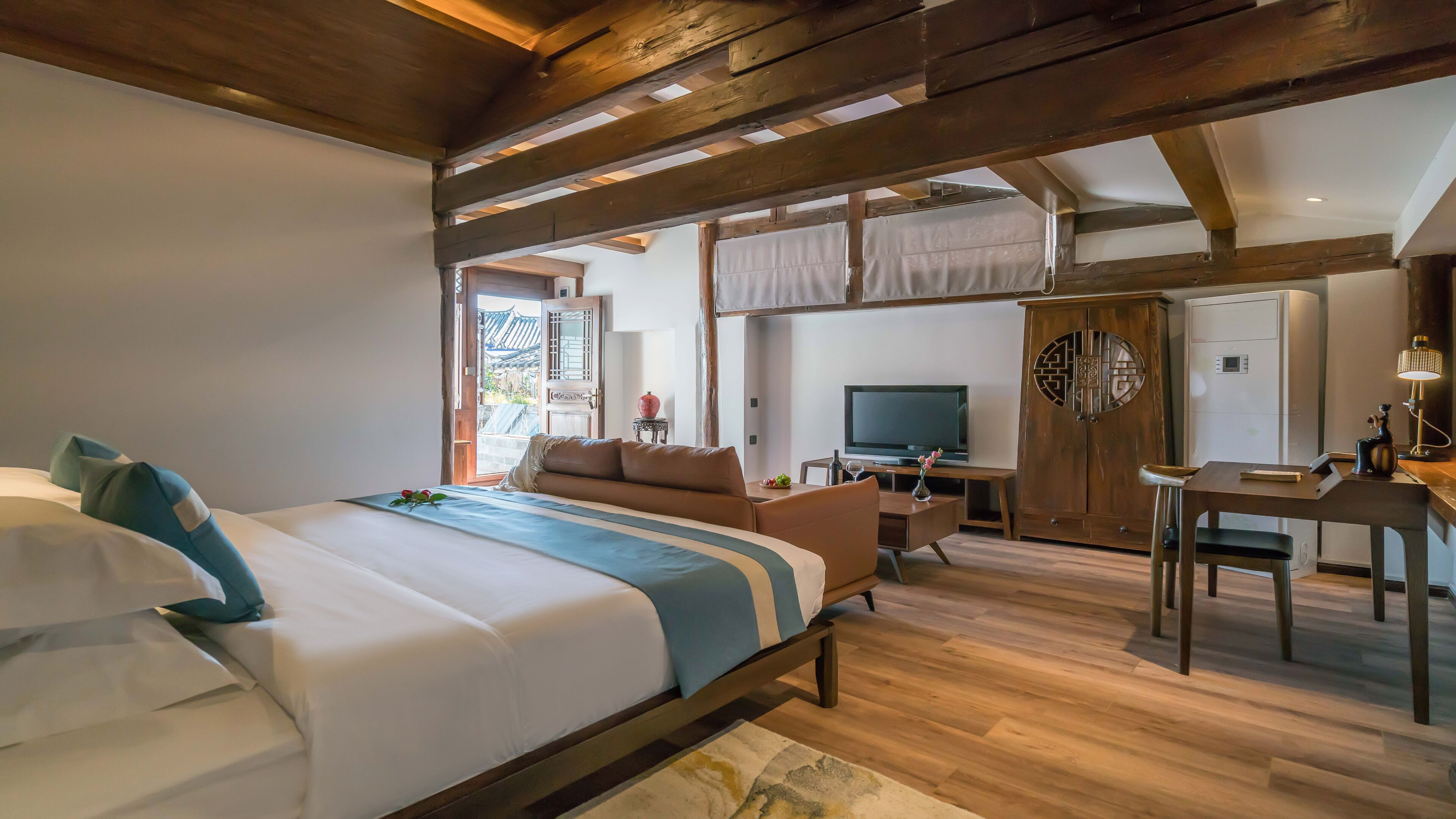 A hotel room with a large bed, a desk, a television, and a wardrobe.