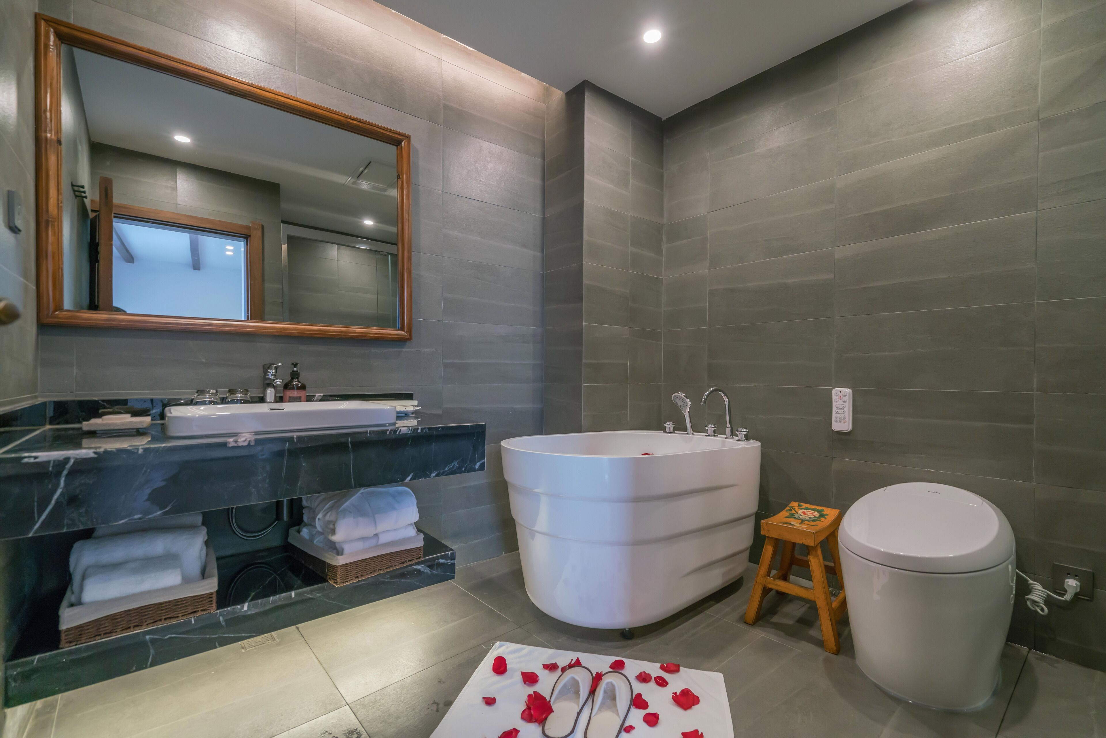 A modern bathroom with a large bathtub, a sink with a mirror, and a toilet.