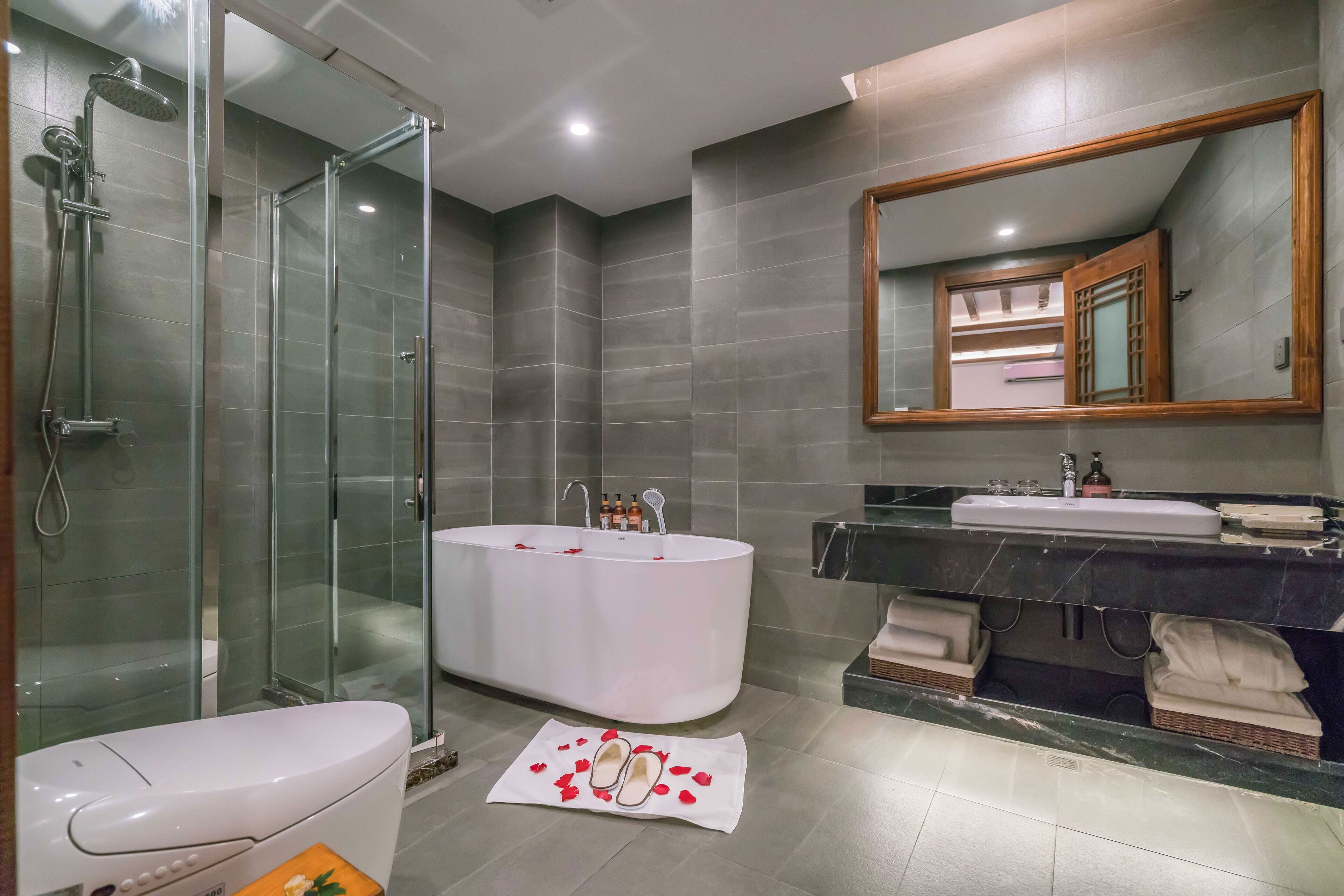 Un baño moderno con ducha de vidrio, bañera independiente y tocador con espejo.