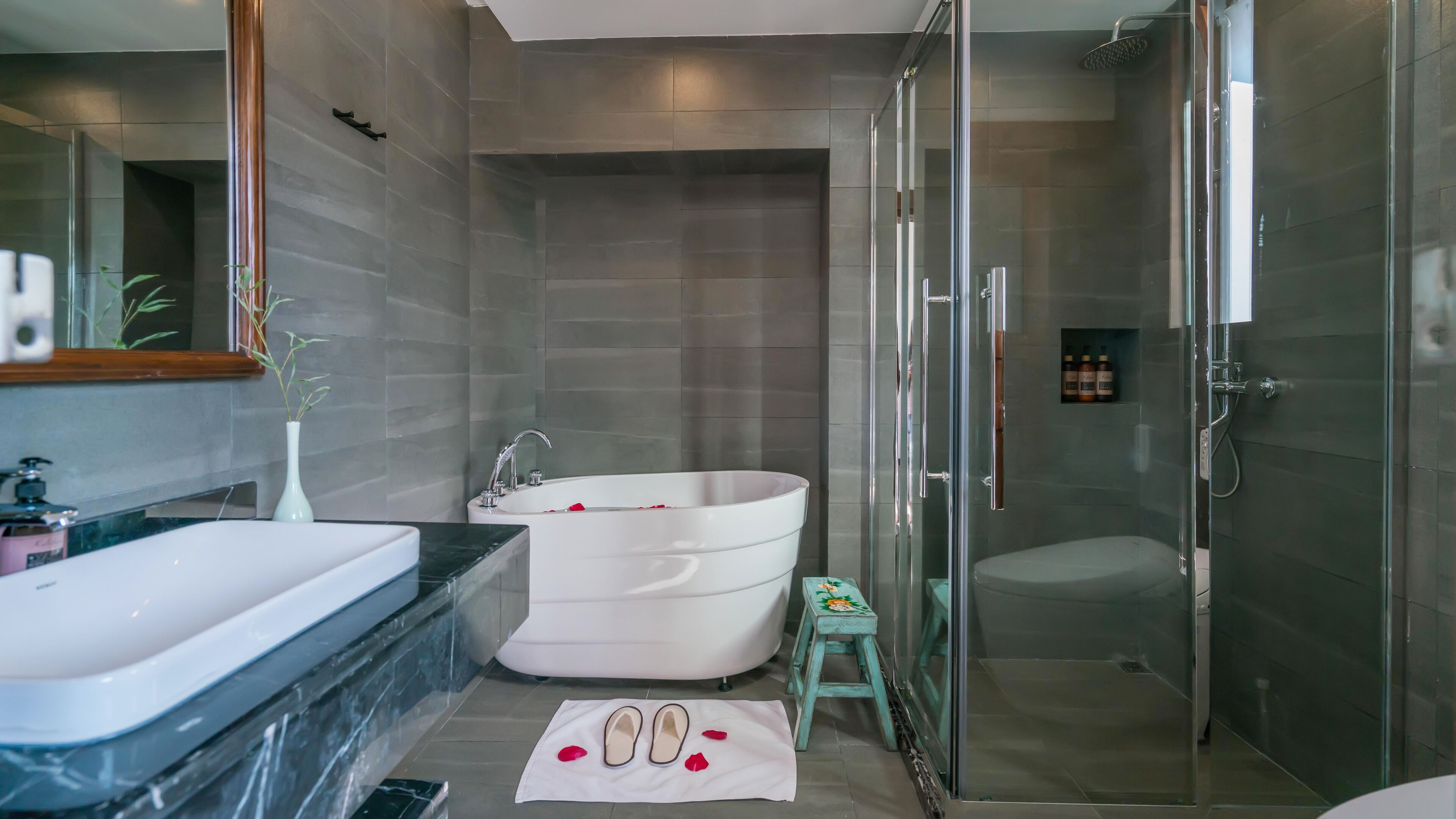 Ein modernes Badezimmer mit freistehender Badewanne, einer Duschkabine und einem Waschtisch mit Marmorplatte.