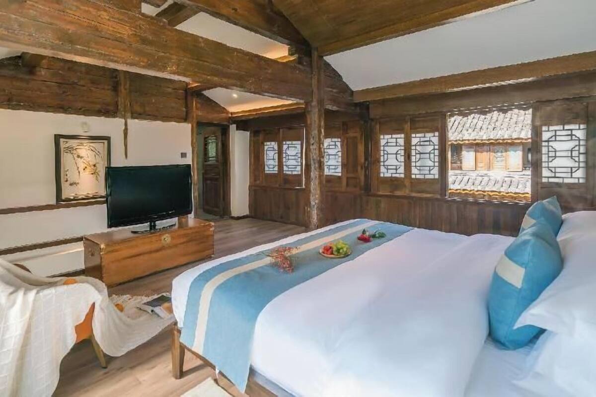 A bedroom with a bed, a TV, and wooden beams.