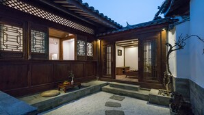 A traditional Japanese-style courtyard with wooden doors, a stone pathway, and a small table with fruit. - Lize Graceland Artistic Suite Inn (Lijiang)