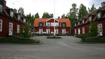 A symmetrical building with a central entrance, surrounded by a gravel driveway and greenery.