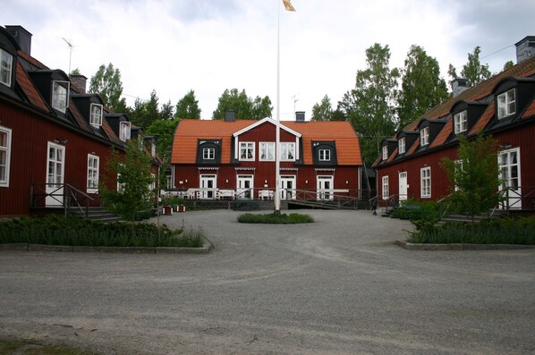 Stately building with a central entrance and two wings, set amidst a landscaped area with a flagpole.