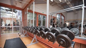 A gym with weightlifting equipment, a black mat, and large windows. - Sätra Brunn Hälsobrunn (Sala)