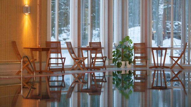 A room with large windows, wooden chairs, a glass table, and a potted plant. - Sätra Brunn Hälsobrunn (Sala)