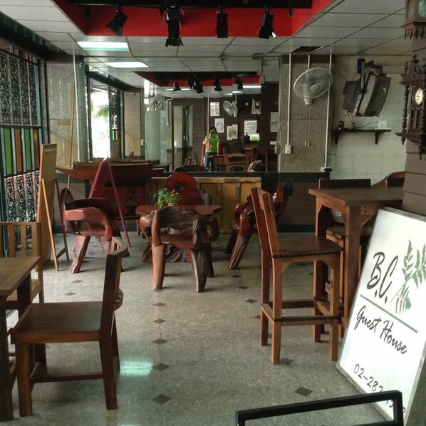 Interior de restaurante con mobiliario de madera, un cartel y un reloj en la pared.