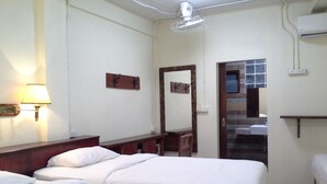 A hotel room with two beds, a bedside table, a lamp, a mirror, and a bathroom visible through an open door. - BC guesthouse Banglamphu (Bangkok)