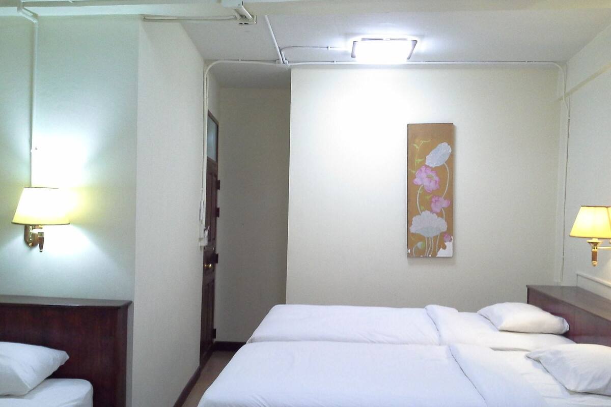 A hotel room with two beds, a nightstand, a lamp, and a painting on the wall.