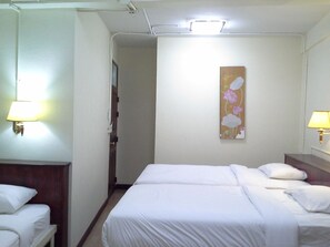 A hotel room with two beds, a nightstand, a lamp, and a painting on the wall. - BC guesthouse Banglamphu (Bangkok)